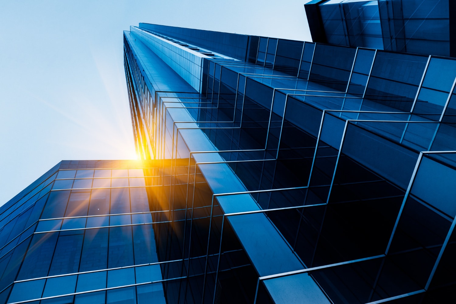 Glass office tower viewed from below at sunrise